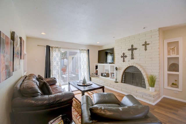 living area with built in shelves, baseboards, a fireplace, wood finished floors, and a textured ceiling