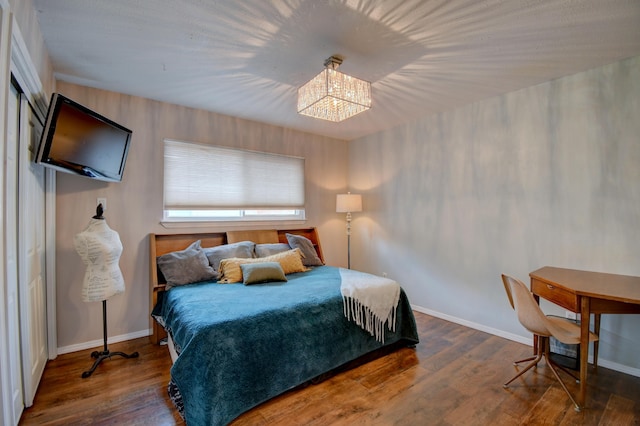 bedroom featuring a notable chandelier, wood finished floors, and baseboards