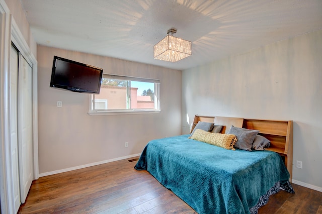 bedroom featuring a notable chandelier, visible vents, baseboards, and hardwood / wood-style floors