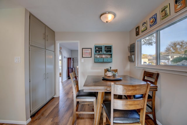 dining space with baseboards and wood finished floors