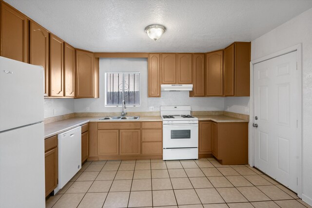 kitchen with a textured ceiling, white appliances, sink, and light tile patterned floors