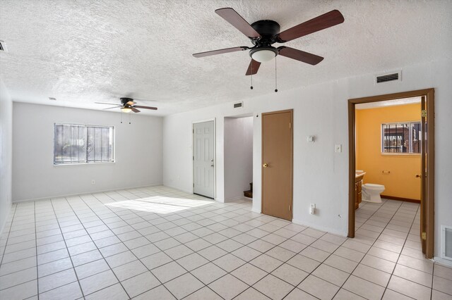 unfurnished room with ceiling fan, light tile patterned floors, and a textured ceiling