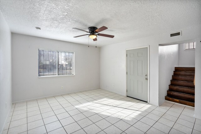 spare room featuring ceiling fan, light tile patterned floors, and a textured ceiling