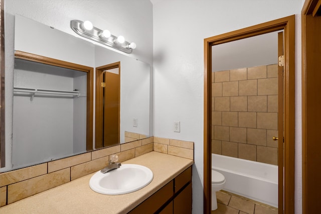 full bathroom with tile patterned floors, vanity, tiled shower / bath combo, and toilet