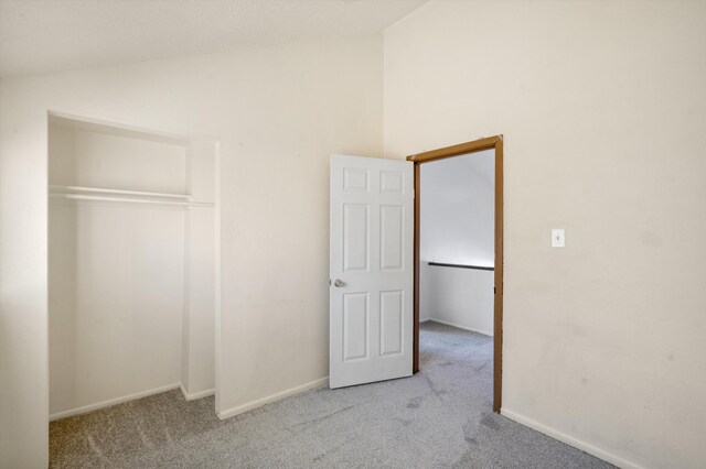 unfurnished bedroom with lofted ceiling, light carpet, and a closet