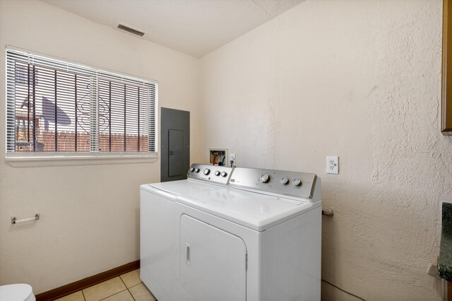 clothes washing area featuring light tile patterned floors, washing machine and dryer, and electric panel