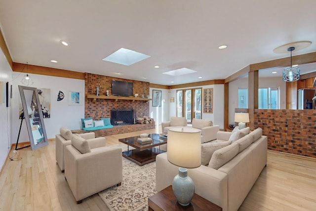 living room with a fireplace, light hardwood / wood-style floors, and a skylight