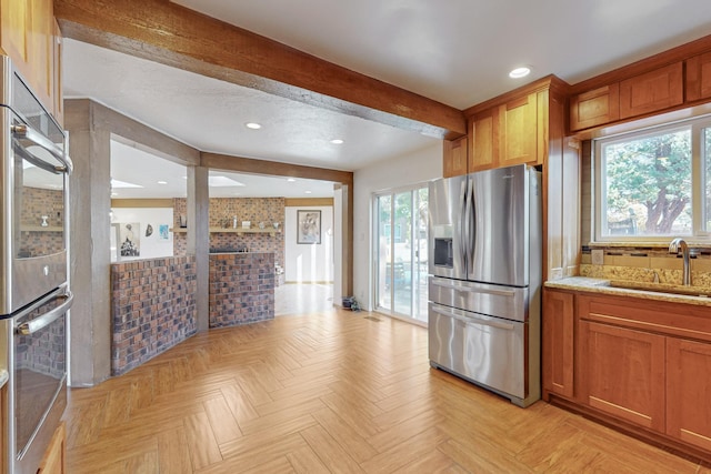 kitchen featuring light stone counters, sink, stainless steel appliances, and light parquet flooring