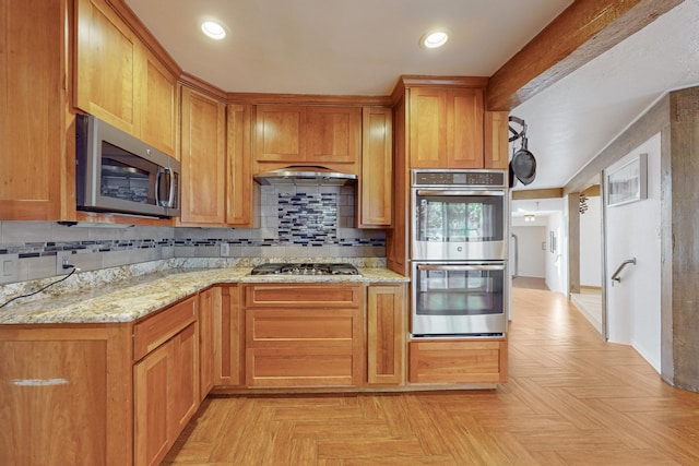 kitchen featuring decorative backsplash, light stone countertops, appliances with stainless steel finishes, and light parquet floors