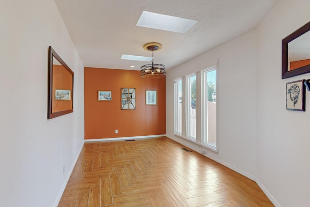 unfurnished room featuring a skylight, light parquet floors, and a notable chandelier