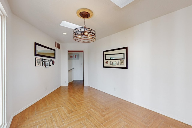 spare room with light parquet floors and a notable chandelier