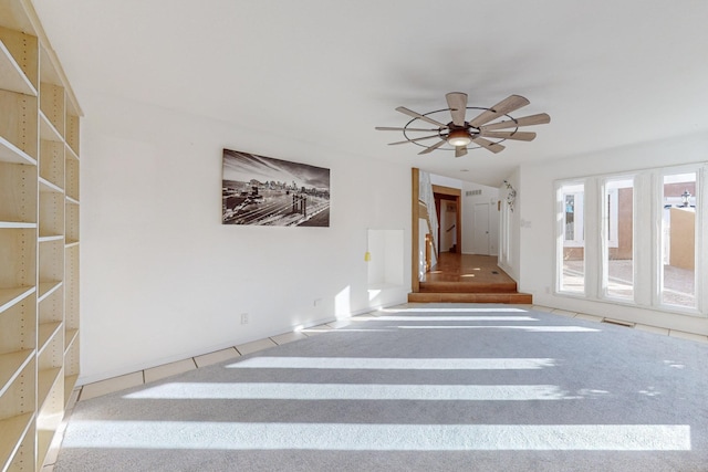 staircase with ceiling fan and carpet