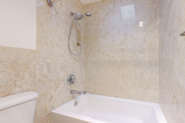 bathroom with toilet, tiled shower / bath, and tile walls