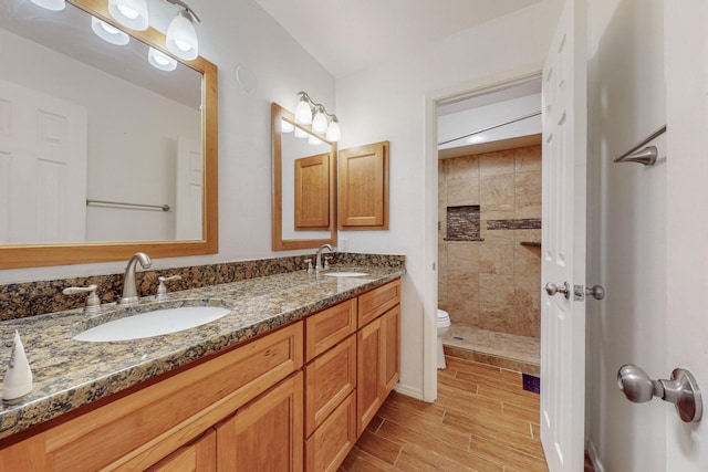 bathroom with vanity, toilet, and a tile shower