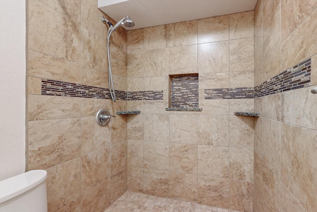 bathroom featuring a tile shower and toilet