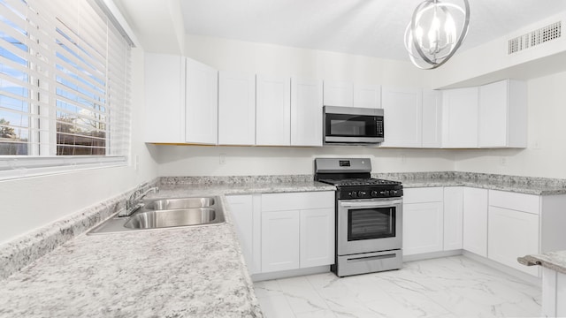 kitchen featuring sink, white cabinetry, stainless steel appliances, and hanging light fixtures