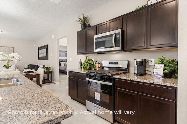 kitchen with appliances with stainless steel finishes, a textured ceiling, light stone counters, and dark brown cabinets