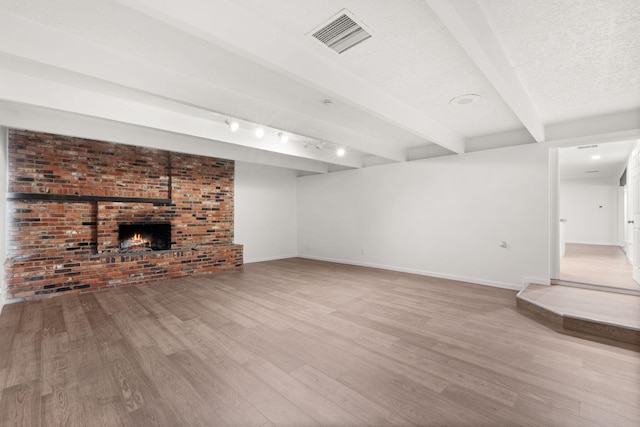 basement with hardwood / wood-style flooring, rail lighting, a fireplace, and a textured ceiling