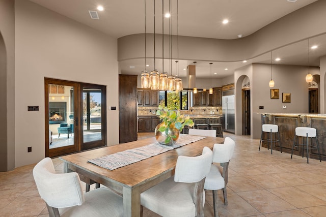 tiled dining room with french doors and a towering ceiling