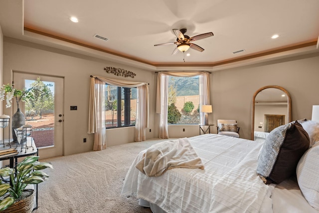 carpeted bedroom featuring ceiling fan, access to exterior, and a tray ceiling