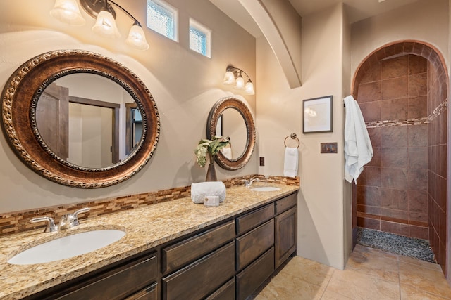 bathroom featuring tile patterned floors, vanity, tiled shower, and backsplash