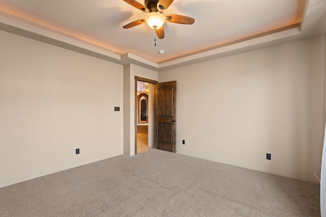 carpeted empty room with a tray ceiling and ceiling fan