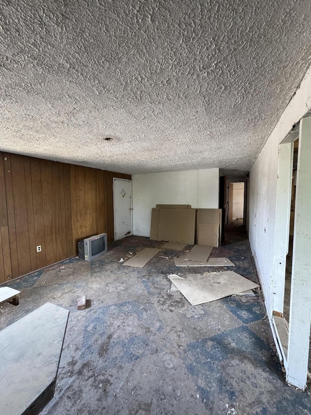 interior space with a textured ceiling and wooden walls