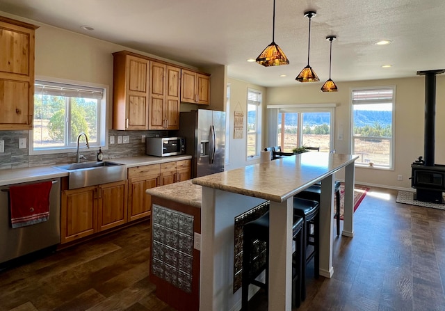 kitchen featuring appliances with stainless steel finishes, backsplash, sink, pendant lighting, and a center island