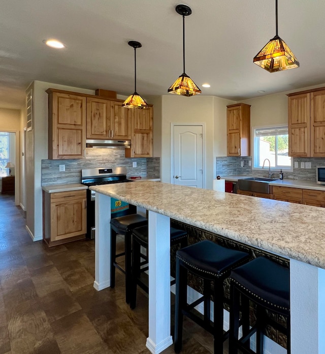 kitchen with a breakfast bar, sink, tasteful backsplash, decorative light fixtures, and stainless steel appliances