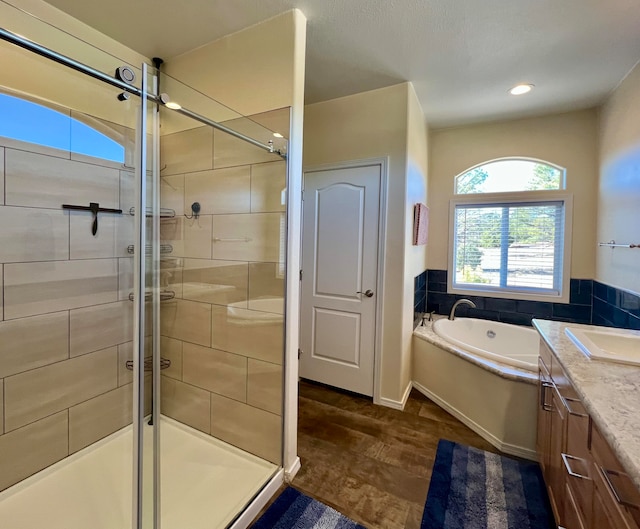 bathroom featuring hardwood / wood-style flooring, vanity, and plus walk in shower