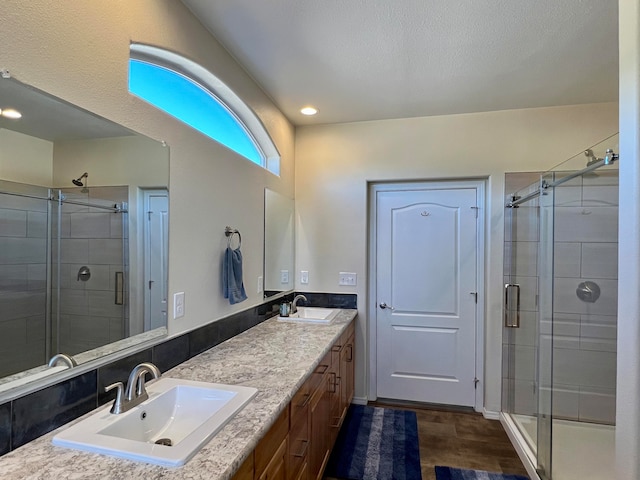 bathroom with vanity, an enclosed shower, and a textured ceiling