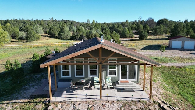 rear view of property with a patio area, a garage, and an outdoor structure