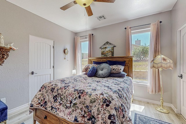 bedroom with light wood-style floors, multiple windows, and visible vents