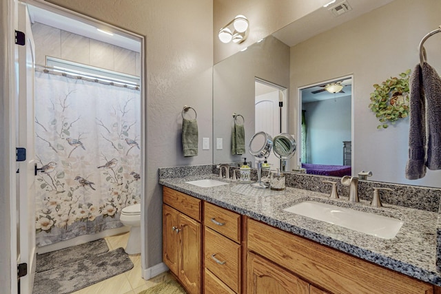 bathroom featuring toilet, double vanity, visible vents, and a sink