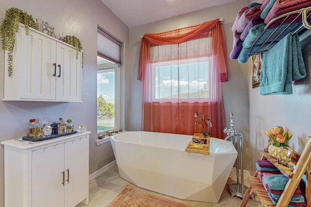 full bathroom featuring a freestanding tub and baseboards