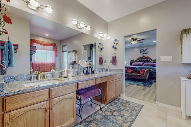 full bathroom featuring a sink, a ceiling fan, baseboards, double vanity, and ensuite bath