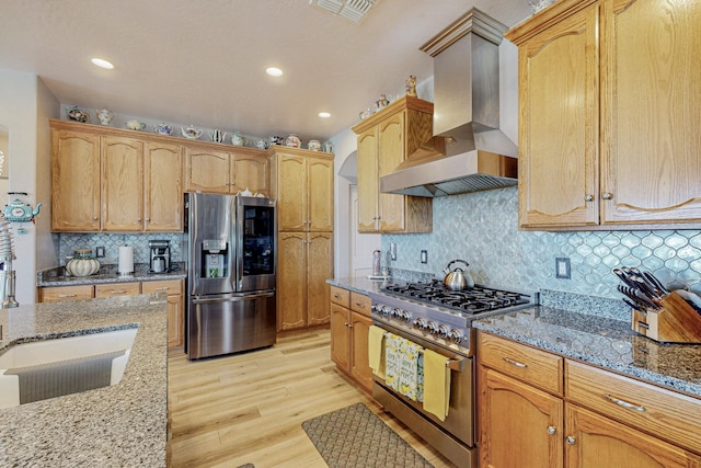 kitchen featuring light stone counters, extractor fan, visible vents, appliances with stainless steel finishes, and light wood-type flooring