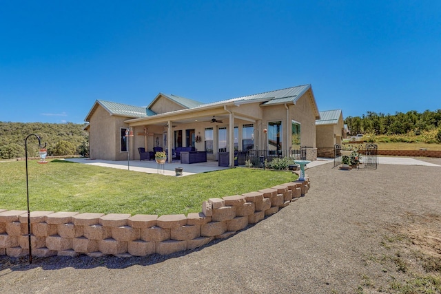 back of house featuring ceiling fan, a patio, metal roof, a yard, and stucco siding