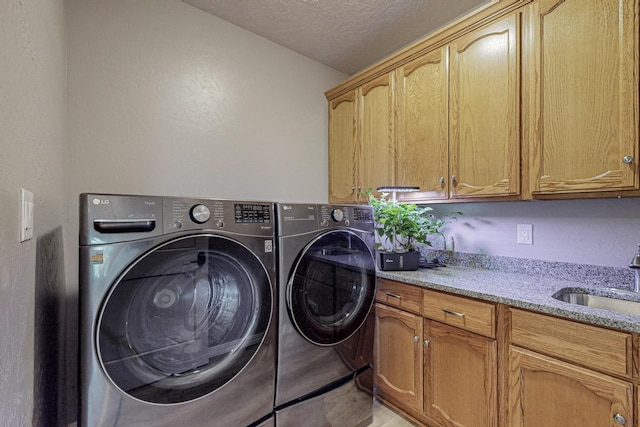 laundry room with a textured ceiling, washer and clothes dryer, a sink, and cabinet space