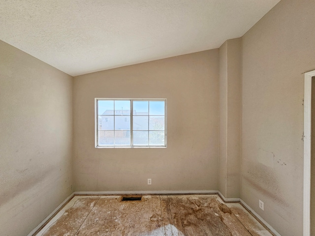 empty room featuring lofted ceiling and a textured ceiling