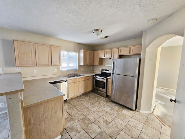 kitchen featuring sink, light brown cabinetry, a textured ceiling, and appliances with stainless steel finishes