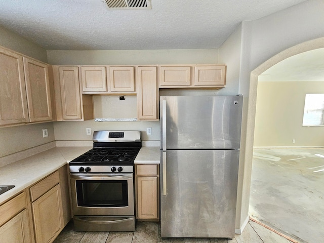 kitchen featuring light brown cabinets, stainless steel appliances, and a textured ceiling