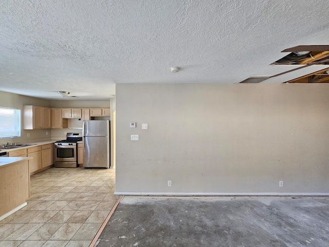 kitchen with a textured ceiling, light brown cabinets, sink, and stainless steel appliances