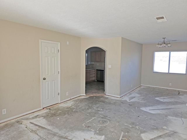 spare room with a notable chandelier and a textured ceiling