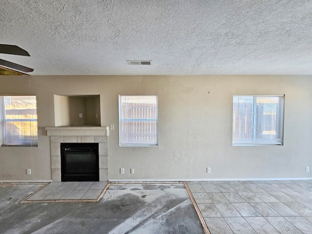 unfurnished living room with a textured ceiling, ceiling fan, and a fireplace