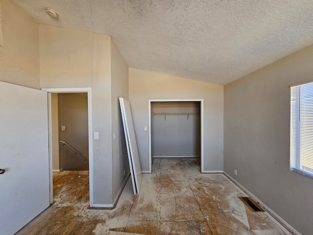 unfurnished bedroom with a textured ceiling, multiple windows, a closet, and vaulted ceiling