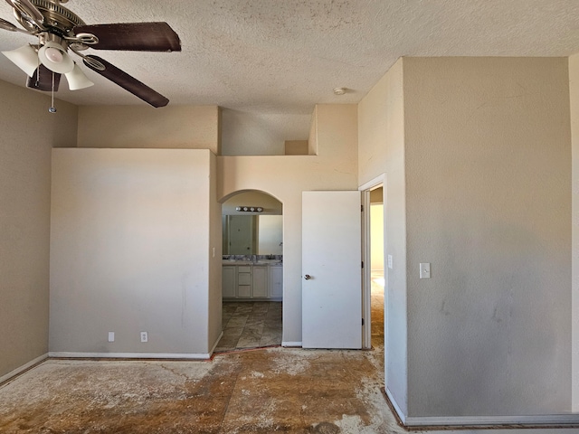 spare room featuring a high ceiling, a textured ceiling, and ceiling fan