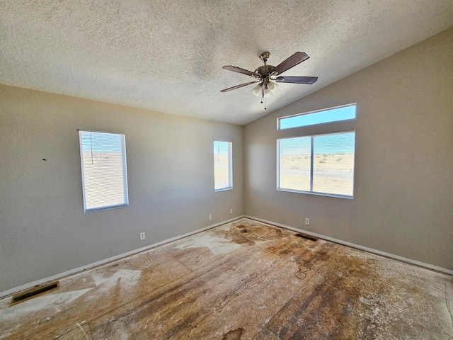 empty room featuring a textured ceiling, vaulted ceiling, and a wealth of natural light