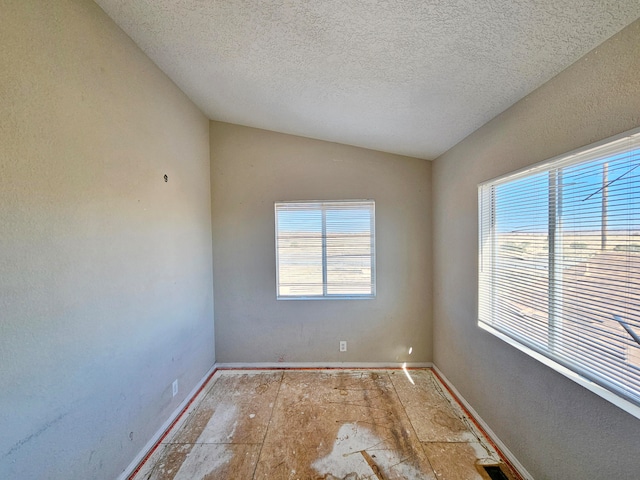 spare room with a textured ceiling and lofted ceiling