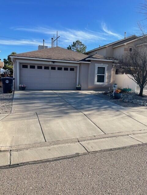 view of front of house featuring concrete driveway, an attached garage, fence, and stucco siding